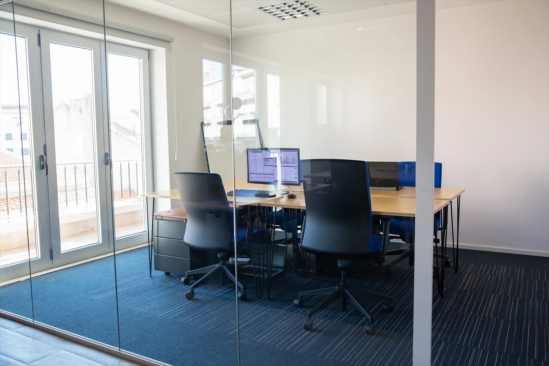 Glass-walled office conference room with workstations